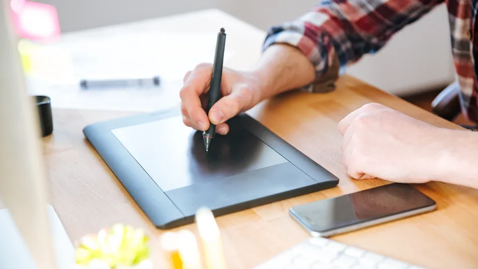 Illustrative photo: Person drawing on a graphics tablet at a desk.