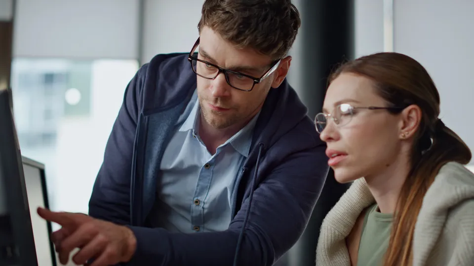 Illustrative photo: Two colleagues looking at a computer screen together.