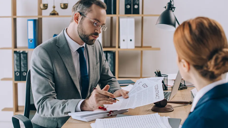 Illustrative photo: Professional reviewing a document with a client across a desk.