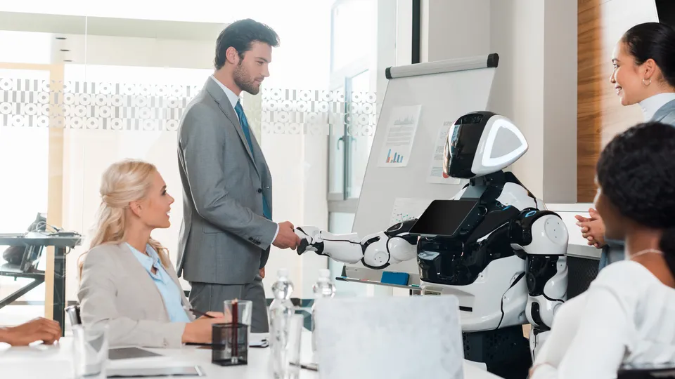Illustrative photo: People meeting with a robot at a table.