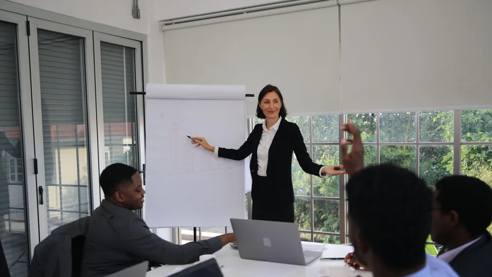 Illustrative photo: Facilitator addressing colleagues beside a flip chart.