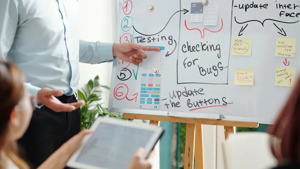 Illustrative photo: Team discussing tasks and testing notes on a planning board.