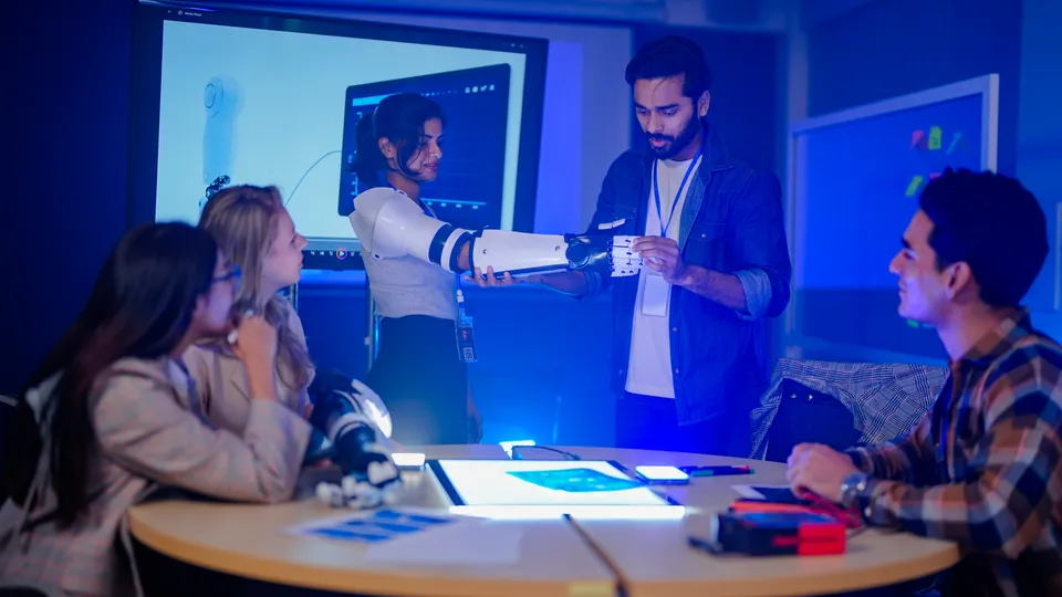 Illustrative photo: Team examining a robotic prosthetic arm in a laboratory.