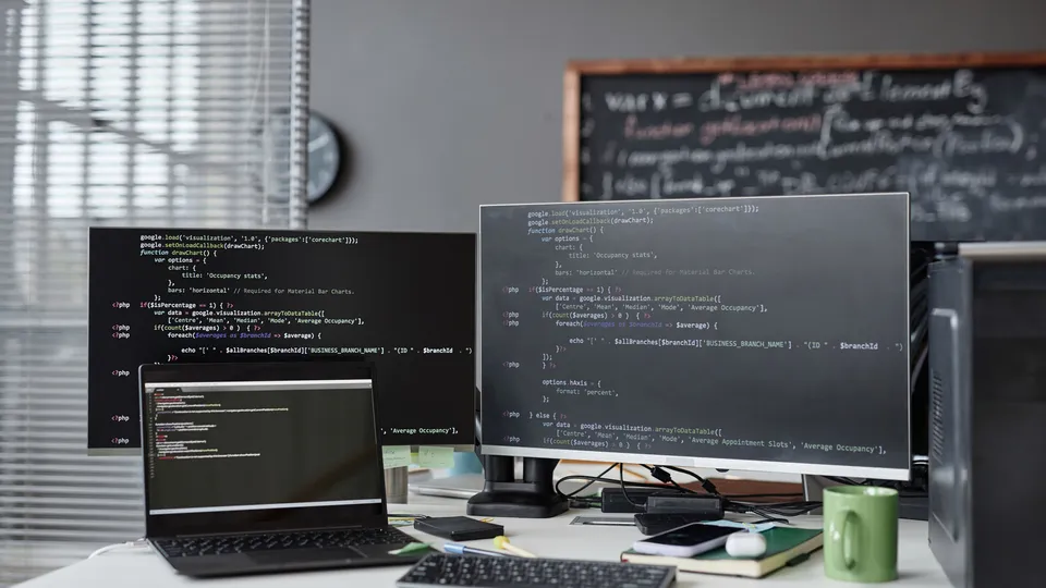 Illustrative photo: Laptop and desktop monitors displaying source code.