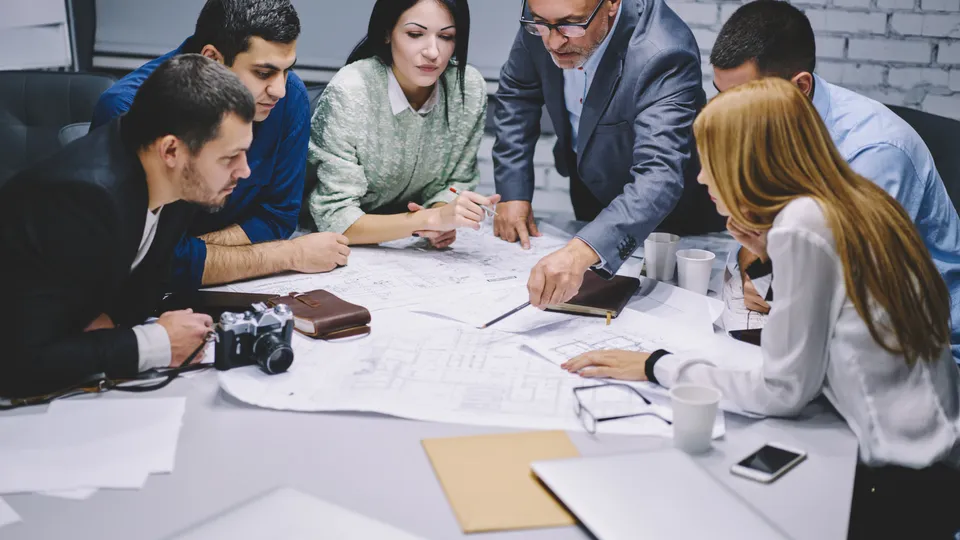 Illustrative photo: Colleagues reviewing documents around a meeting table.