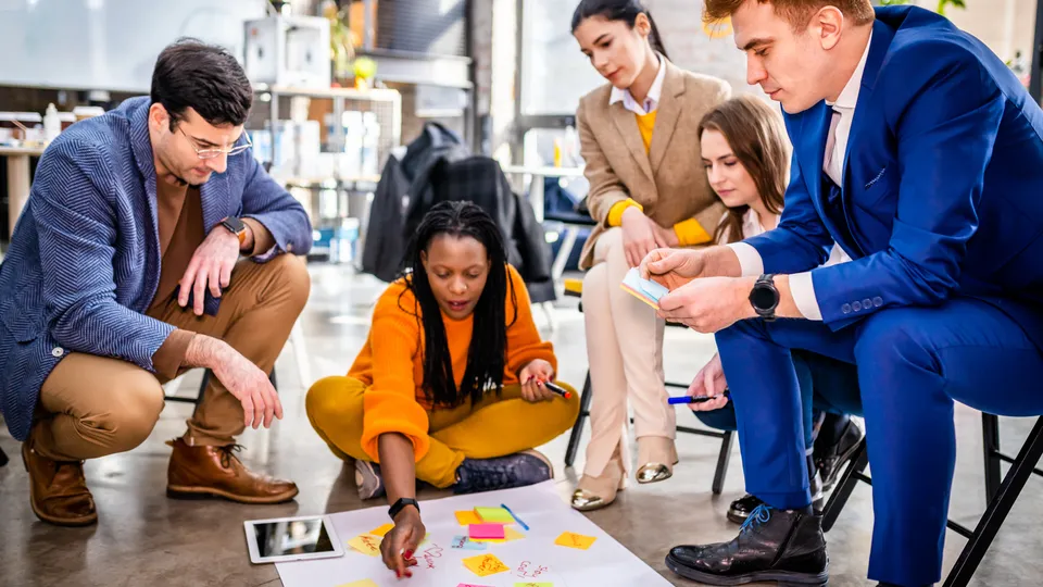 Illustrative photo: Team collaborating around a table covered with sticky notes.