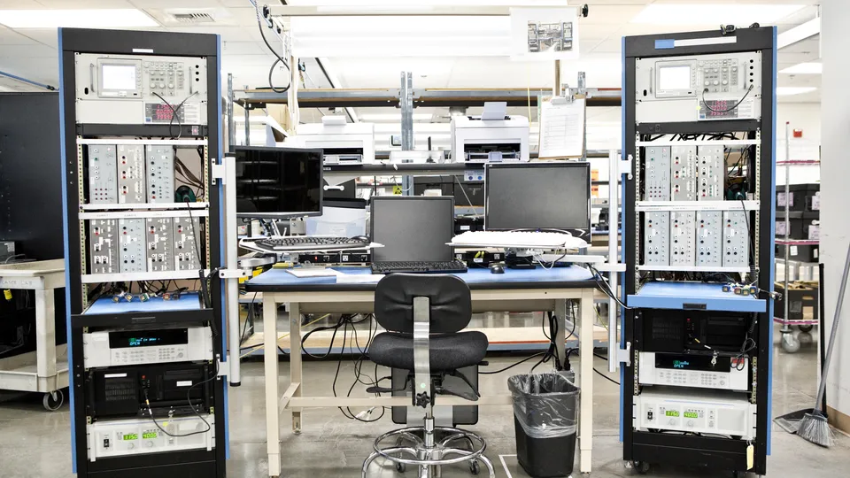 Illustrative photo: Laboratory workspace with racks of electronic test equipment.