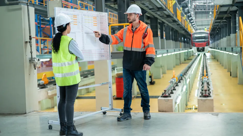 Illustrative photo: Workers reviewing a plan inside a manufacturing facility.