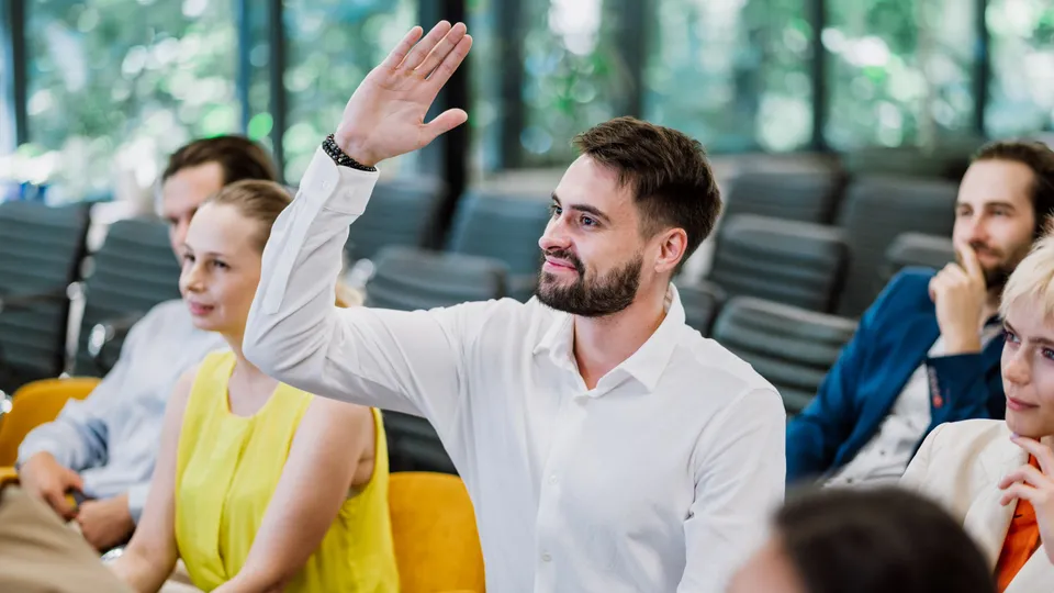 Illustrative photo: Audience member raising a hand during a seminar.
