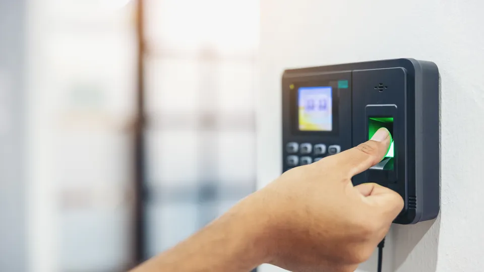 Illustrative photo: Person touching a fingerprint reader at an entrance.