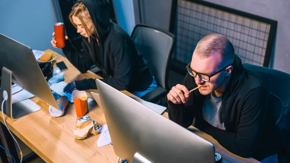 Illustrative photo: Colleagues working at computers in a dark office.