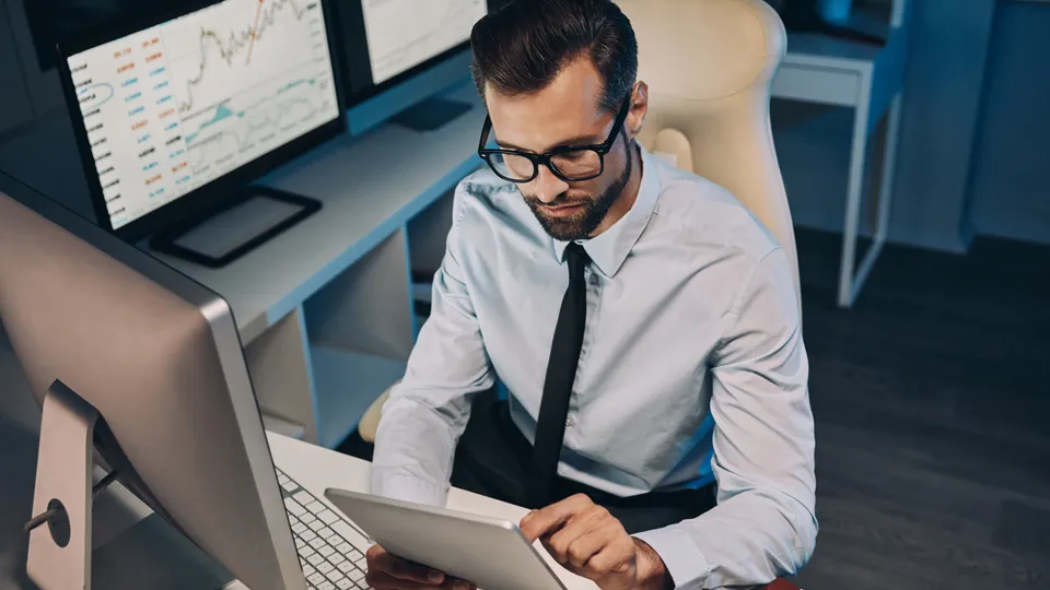 Illustrative photo: Man using a tablet at a desk.