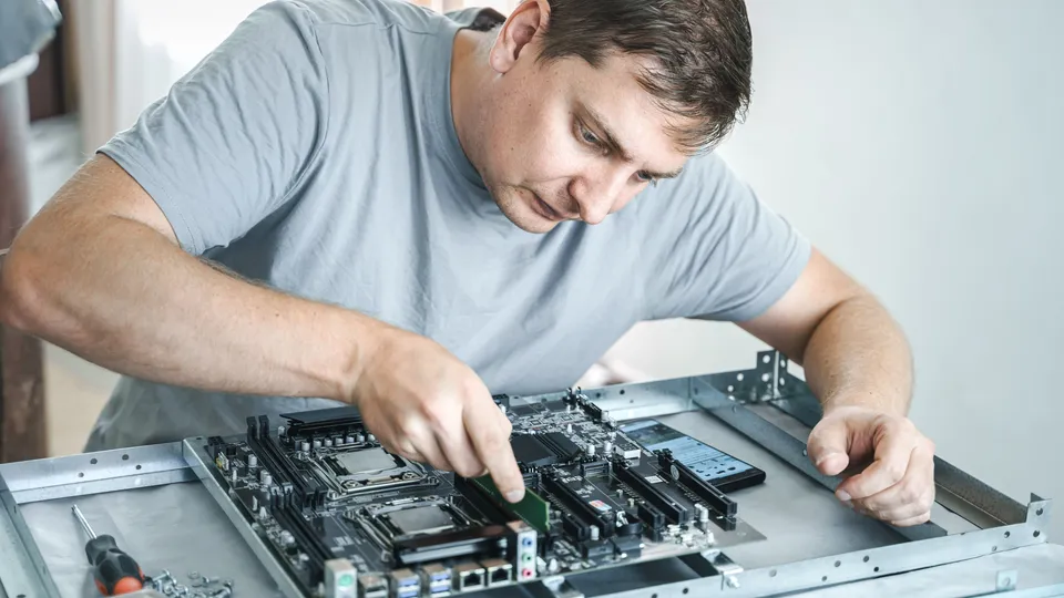 Illustrative photo: Technician assembling components inside an open computer chassis.
