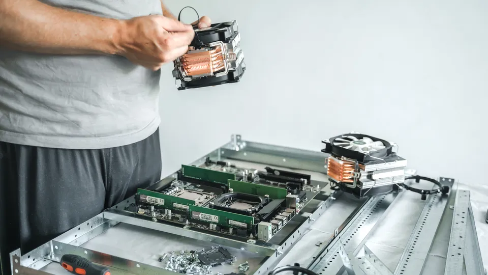 Illustrative photo: Hands installing a component inside an open computer chassis.
