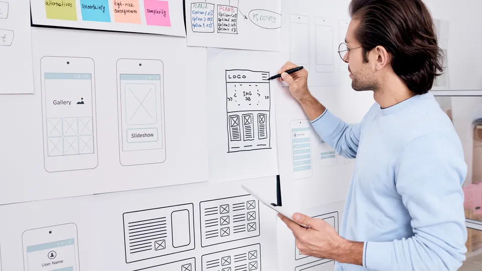Illustrative photo: Designer drawing mobile app wireframes on a whiteboard.
