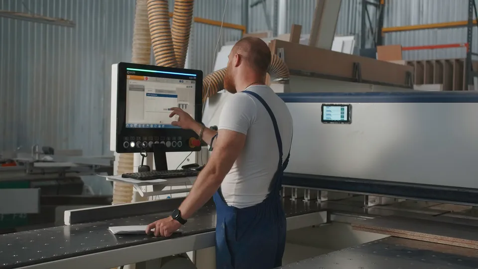Illustrative photo: Operator using a computer-controlled machine in a workshop.