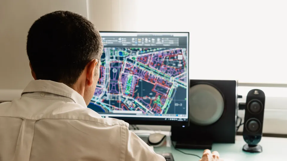 Illustrative photo: Man examining a detailed city map on a computer monitor.