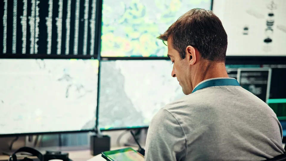 Illustrative photo: Operator working at a workstation with several monitoring screens.