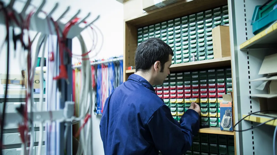 Illustrative photo: Technician selecting a cartridge from shelves of backup tapes.