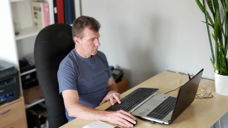 Illustrative photo: Man working on a laptop at a desk in a home office.