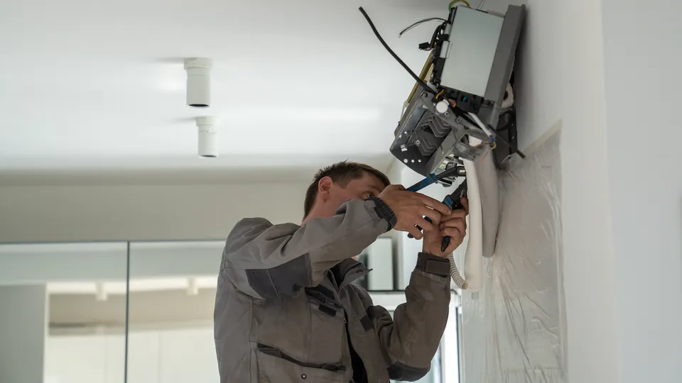 Illustrative photo: Technician servicing an indoor air conditioning unit.