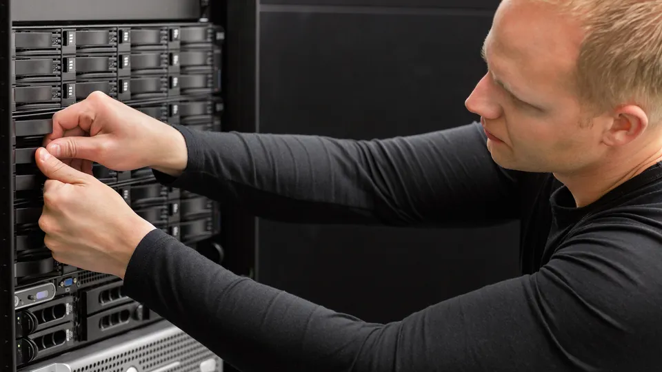 Illustrative photo: Technician handling a component at the front of a rack server.