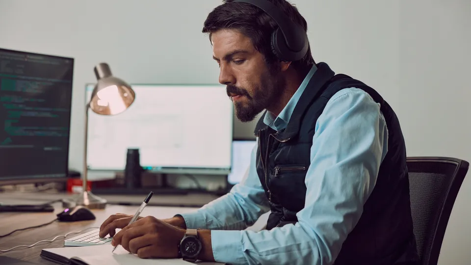Illustrative photo: Man wearing a headset while working at a laptop.