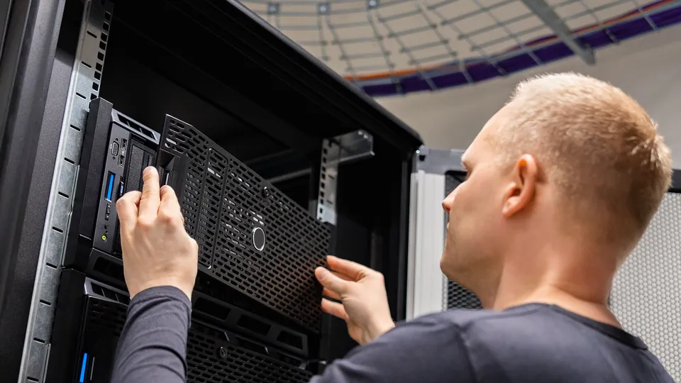 Illustrative photo: Technician handling server hardware in a rack.
