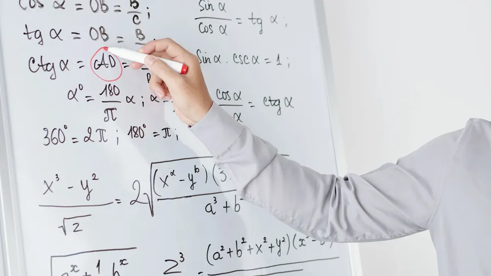 Illustrative photo: Hand writing mathematical formulas on a whiteboard.