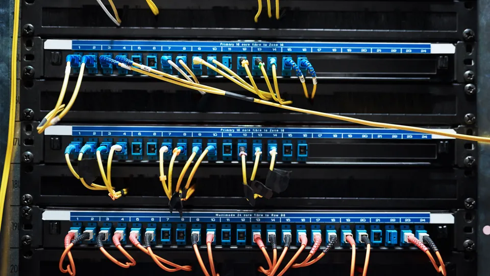 Illustrative photo: Network patch panels with connected cables in a rack.
