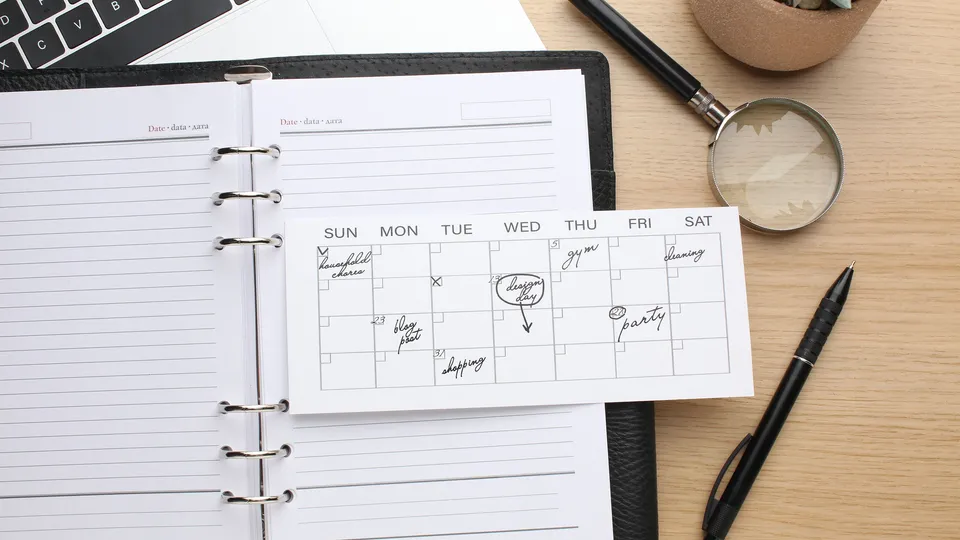 Illustrative photo: Open planner and weekly calendar beside a laptop.