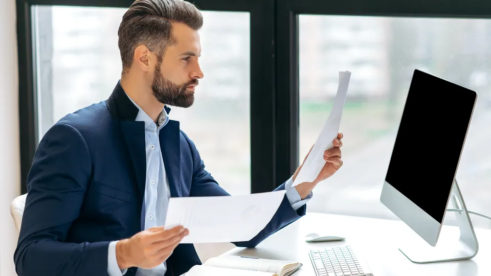 Illustrative photo: Man reviewing documents at an office desk.