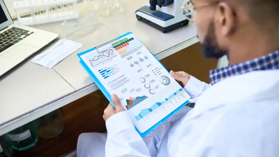 Illustrative photo: Researcher reviewing printed charts at a laboratory desk.