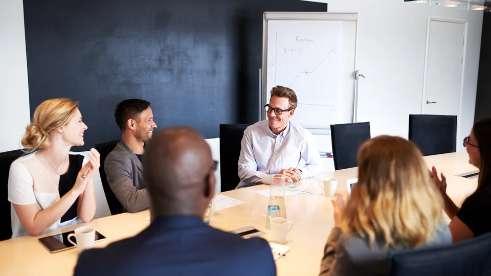 Illustrative photo: Colleagues smiling at a boardroom meeting.