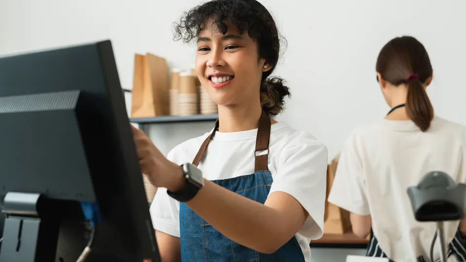 Illustrative photo: Store employee working at a checkout computer.