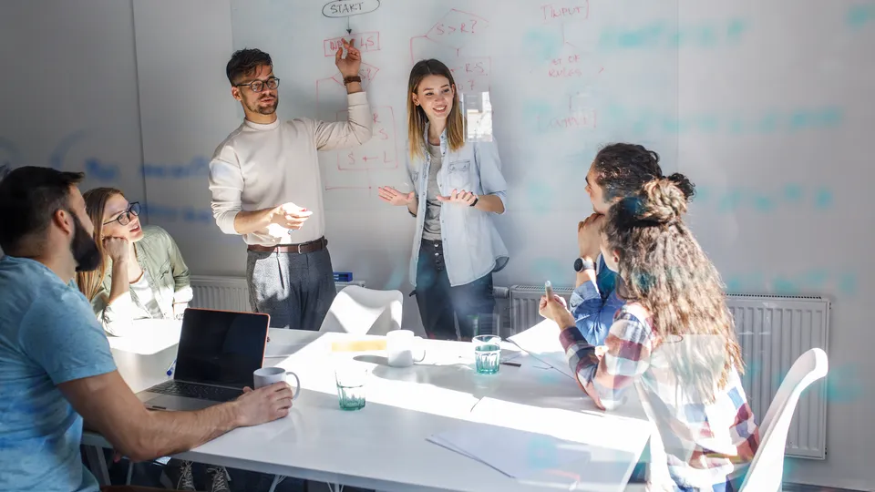 Illustrative photo: Colleagues discussing ideas around a whiteboard.