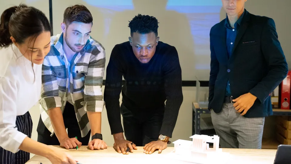 Illustrative photo: Team reviewing an architectural model and drawings.