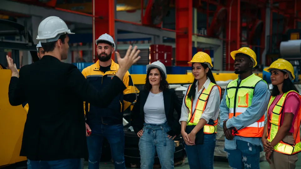 Illustrative photo: Group wearing protective equipment during a factory briefing.