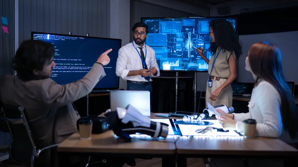 Illustrative photo: Technical team discussing information on large monitoring screens.