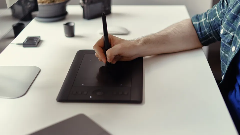 Illustrative photo: Person drawing with a stylus on a graphics tablet.