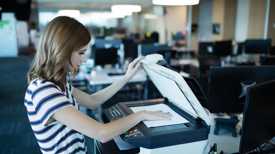 Illustrative photo: Woman placing a document on an office scanner.