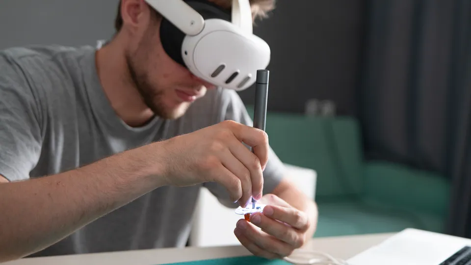 Illustrative photo: Man wearing a headset while working on small electronic components.